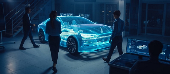 A group of people examine a digital hologram of a car in a modern, high-tech studio, with one person monitoring data on a computer screen.