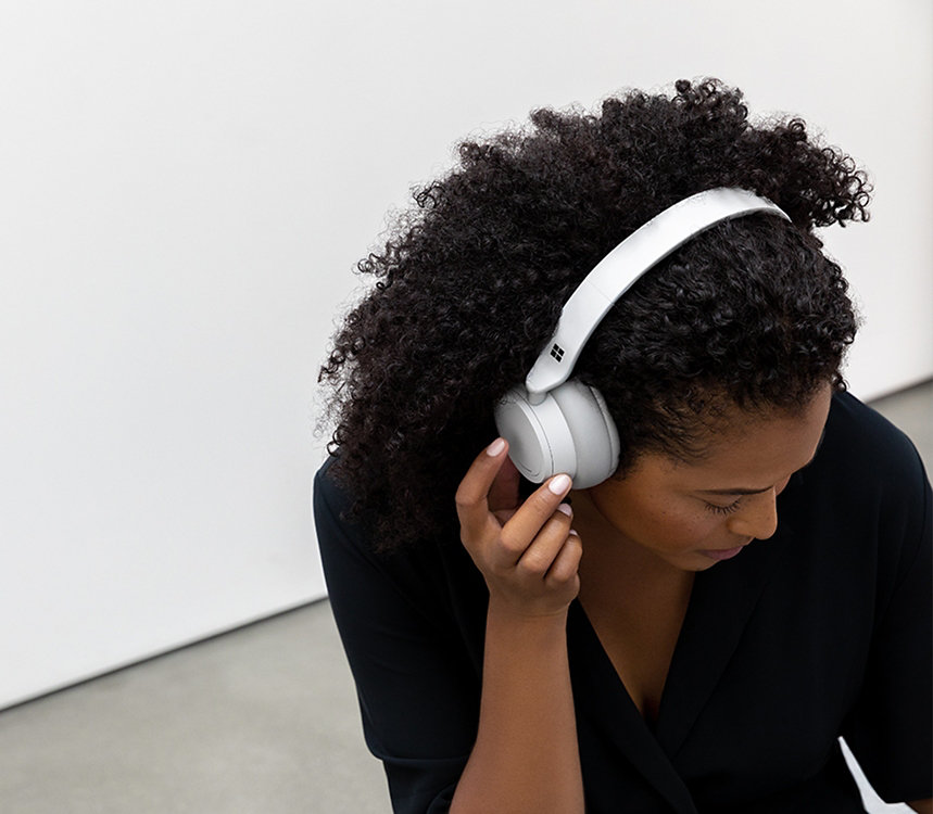 En person lytter til musik med Surface Headphones.