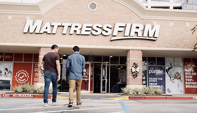 שני אנשים עומדים מול החנות של Mattress Firm.