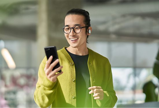 A person wearing earbuds looking at a mobile phone