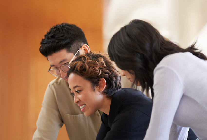 Three people smiling and leaning over together