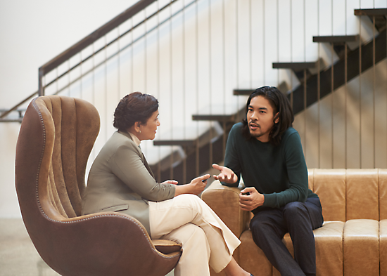 Twee personen die in een lounge zitten en een gesprek voeren