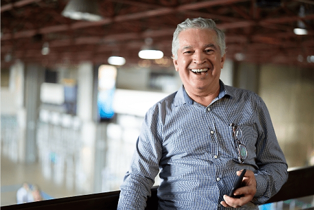 Una persona sonriendo y sosteniendo un teléfono móvil