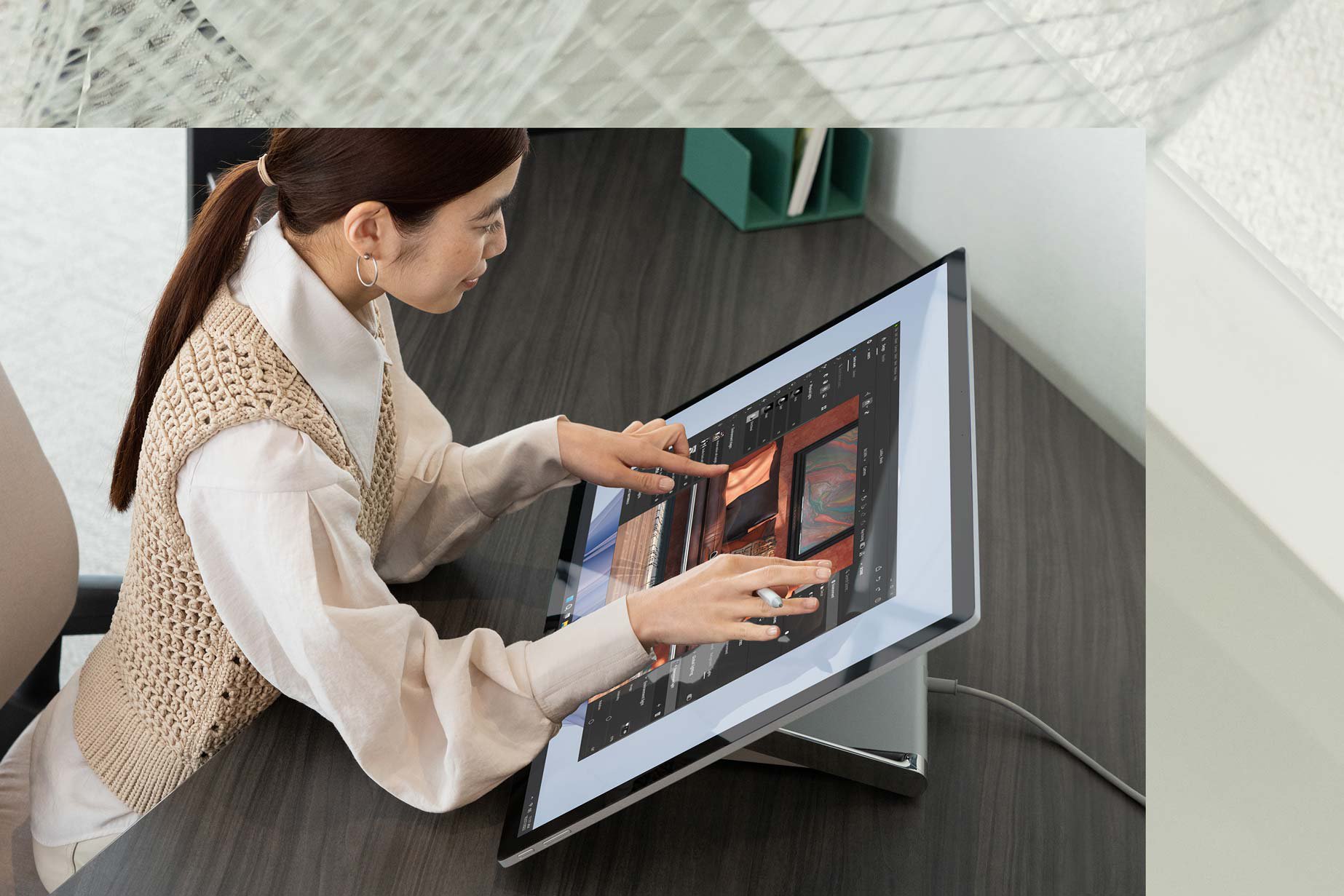En person bruker to hender til å fullføre oppgaver på kontoret og berører en Surface Studio 2+.