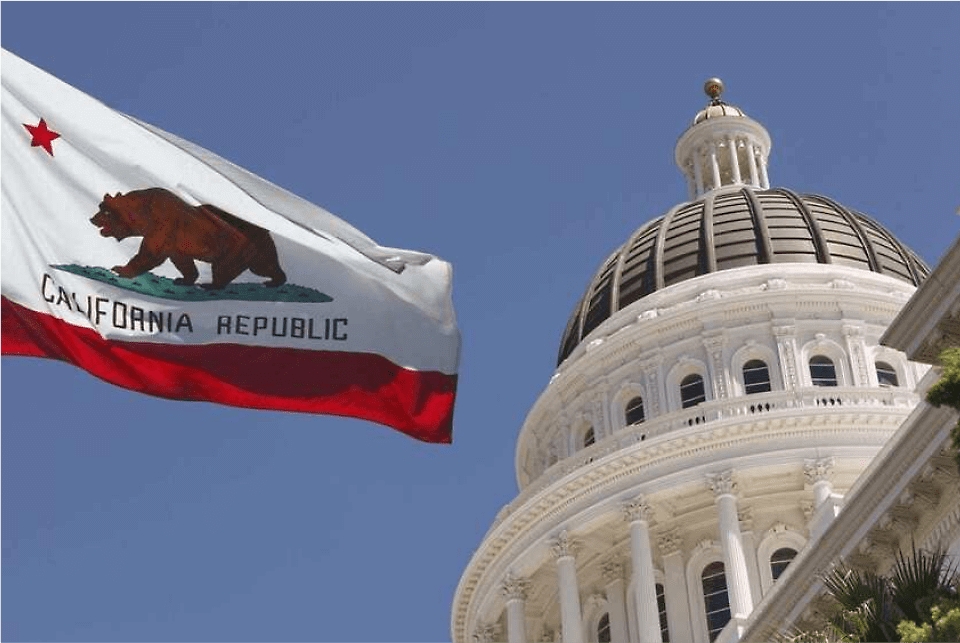 The California state flag flying outside of a government building