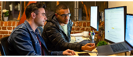 Two people discussing something in front of desktop