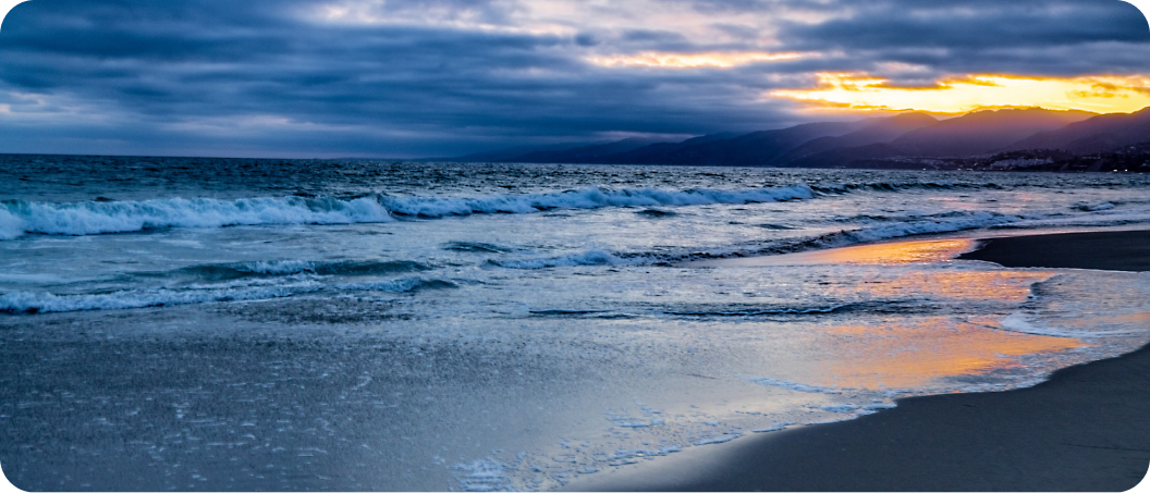 A beach with waves and a sunset