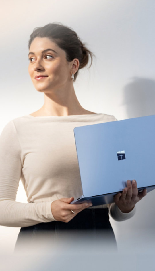 A person holding a 13.8" Surface Laptop in Sapphire.