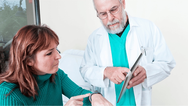 A medical professional showing a patient information on a tablet