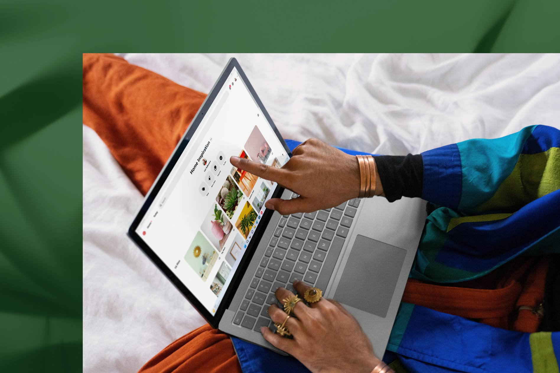 Henkilö koskettaa platinanvärisen Surface Laptop 5 -laitteensa näyttöä työskennellessään vuoteessa.
