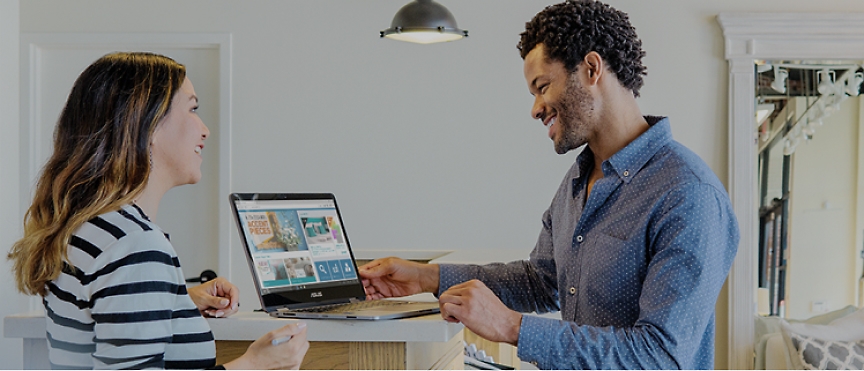 Um homem e uma mulher olhando para um laptop em uma casa.