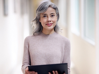 A woman is standing and holding a tablet.