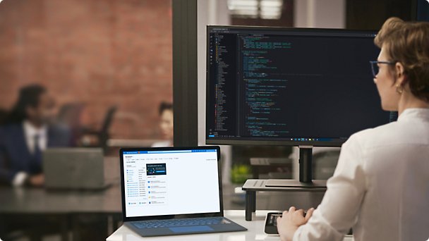 A person using a tablet wearing headphones and multiple screens are placed on the table