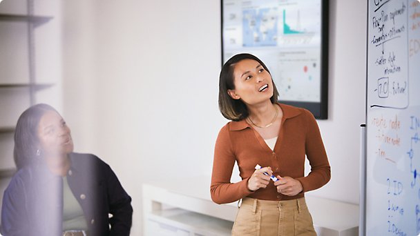 A person speaking while working on a white board with marker