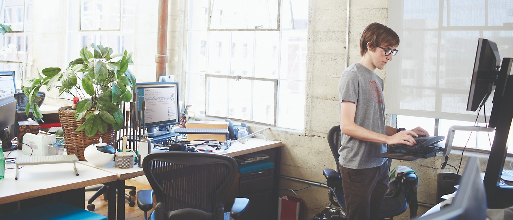 A person standing in his office and working on a desktop