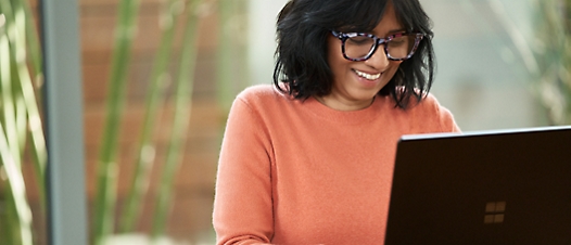 Personne portant des lunettes et souriant tout en tenant une tablette