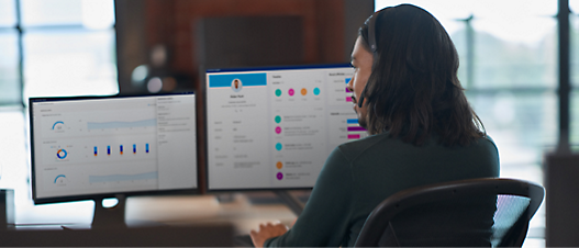 A woman sitting at a desk with two monitors.