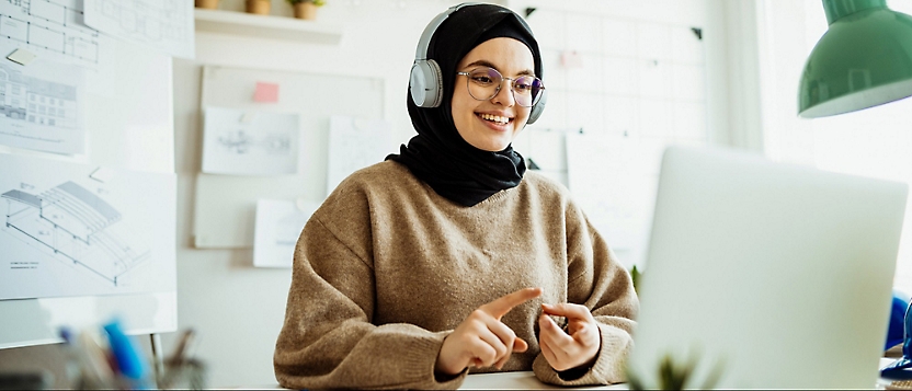 A person wearing headphones and a brown sweater.