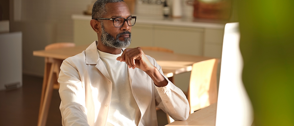 Un homme assis sur une chaise et travaillant sur son ordinateur de bureau