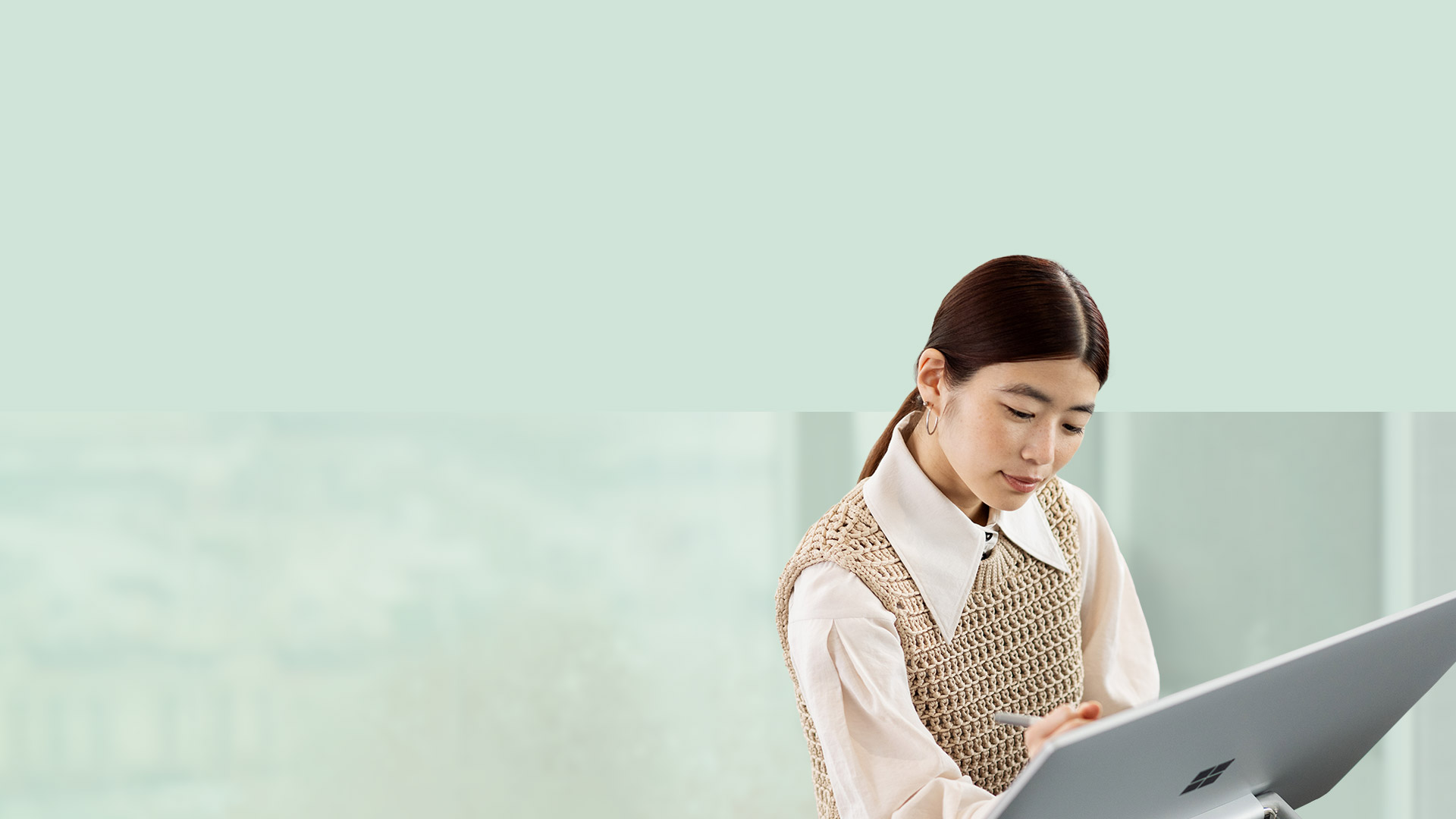 A person is seen using Surface pen to write on the surface of Surface Studio 2+.