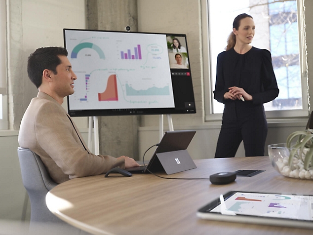 Two people working together looking at a desktop monitor