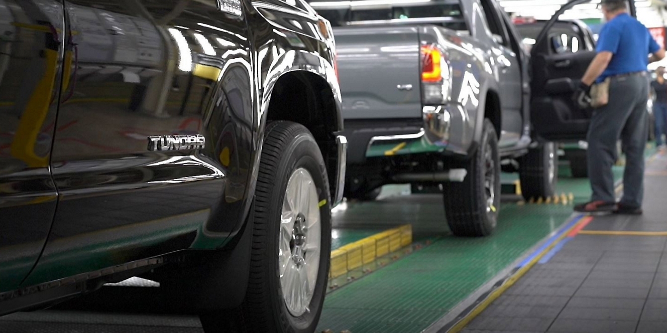 A series of trucks in a factory with a man inspecting one