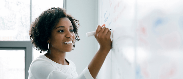 A women writing something in a white board using pen