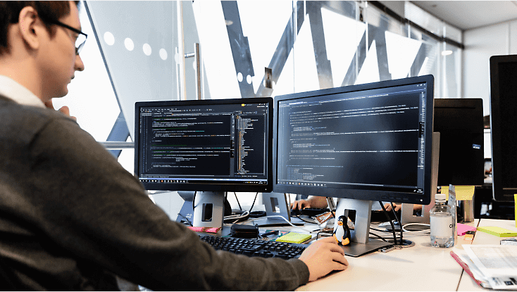 A person working at their desk with multiple screens