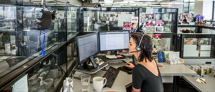 A person sitting at a desk with a headset working on two dekstop