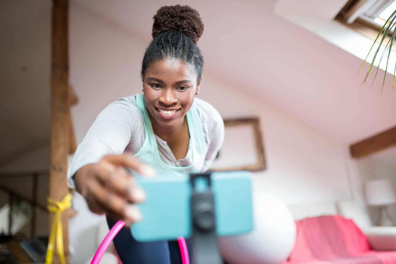 A person leans over a phone on a tripod to start a video recording