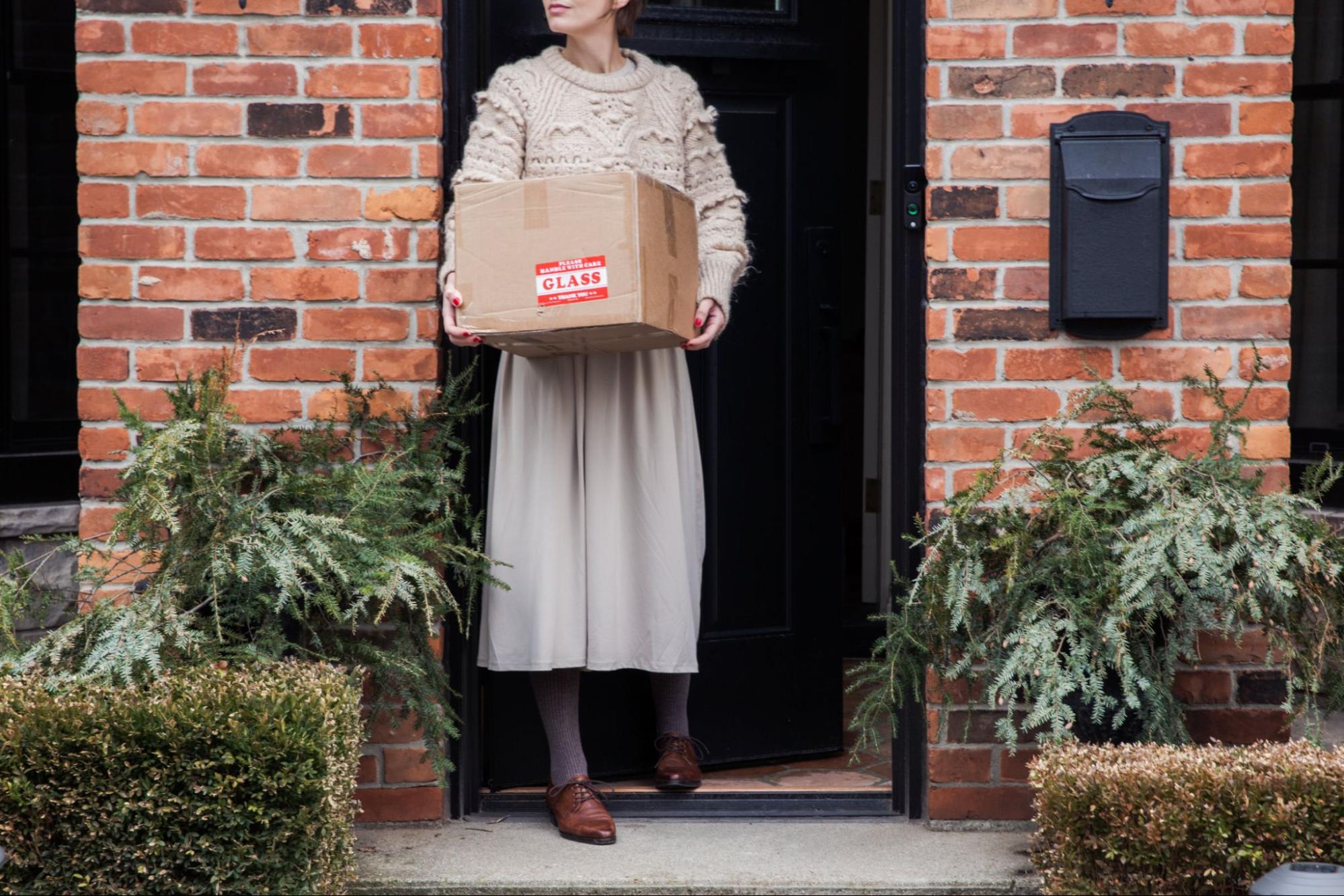 A woman thanks the postal carrier who delivered her package before heading inside her home.