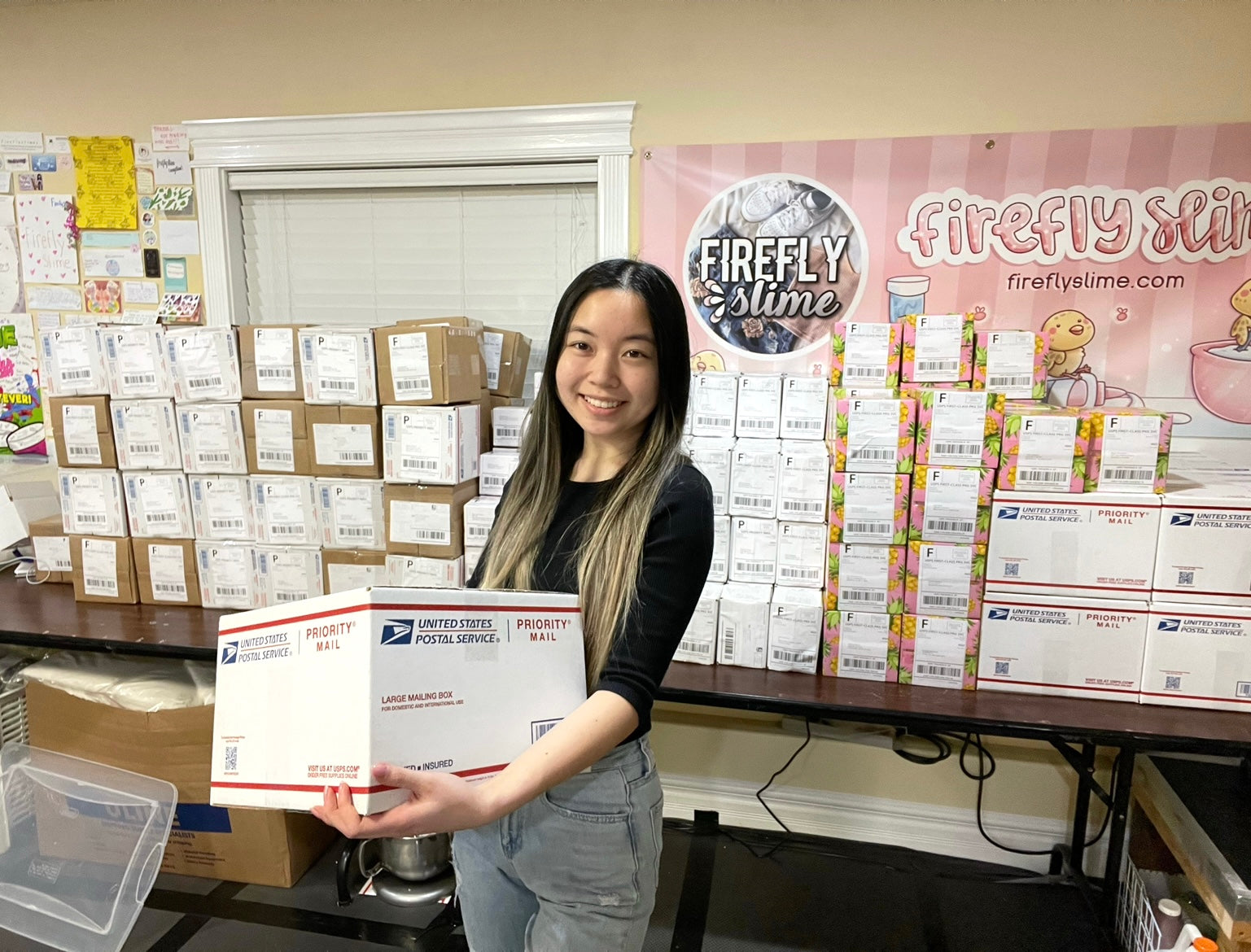 image of the firefly Slime founder holding a large package, standing in front of other packages waiting to be shipped