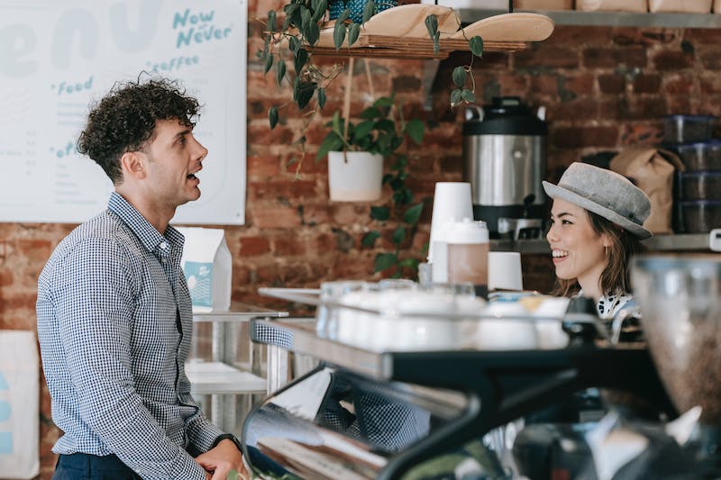 A customer talks to a retail employee in a cafe