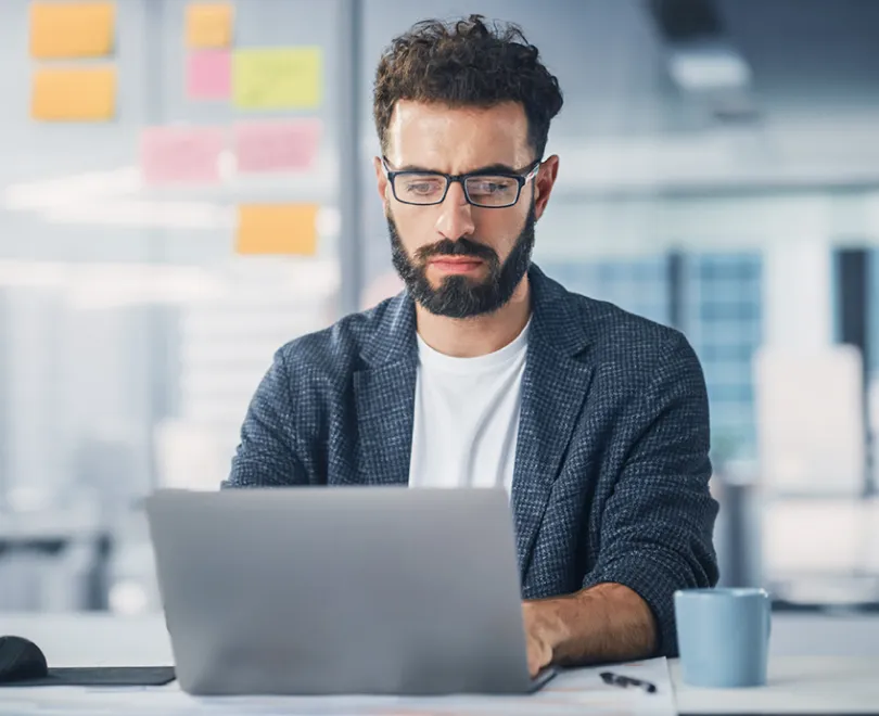 Un homme avec une barbe et des lunettes utilisant un ordinateur portable.