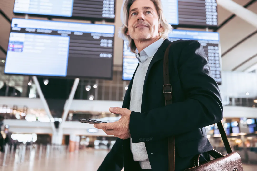 Une personne marchant dans un aéroport avec son téléphone à la main.