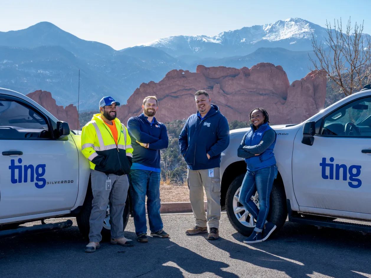 Members of the Ting team stand in front of a mountainous view in Colorado next to two Ting pickup trucks