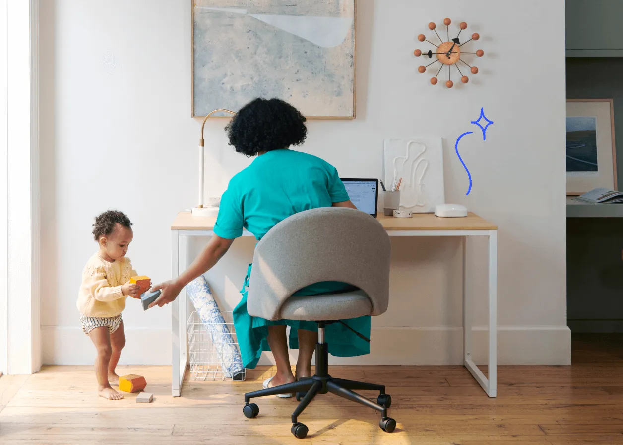 Toddler vies for parent’s attention while parent works on a laptop. A Wi-Fi device sits neatly beside them.