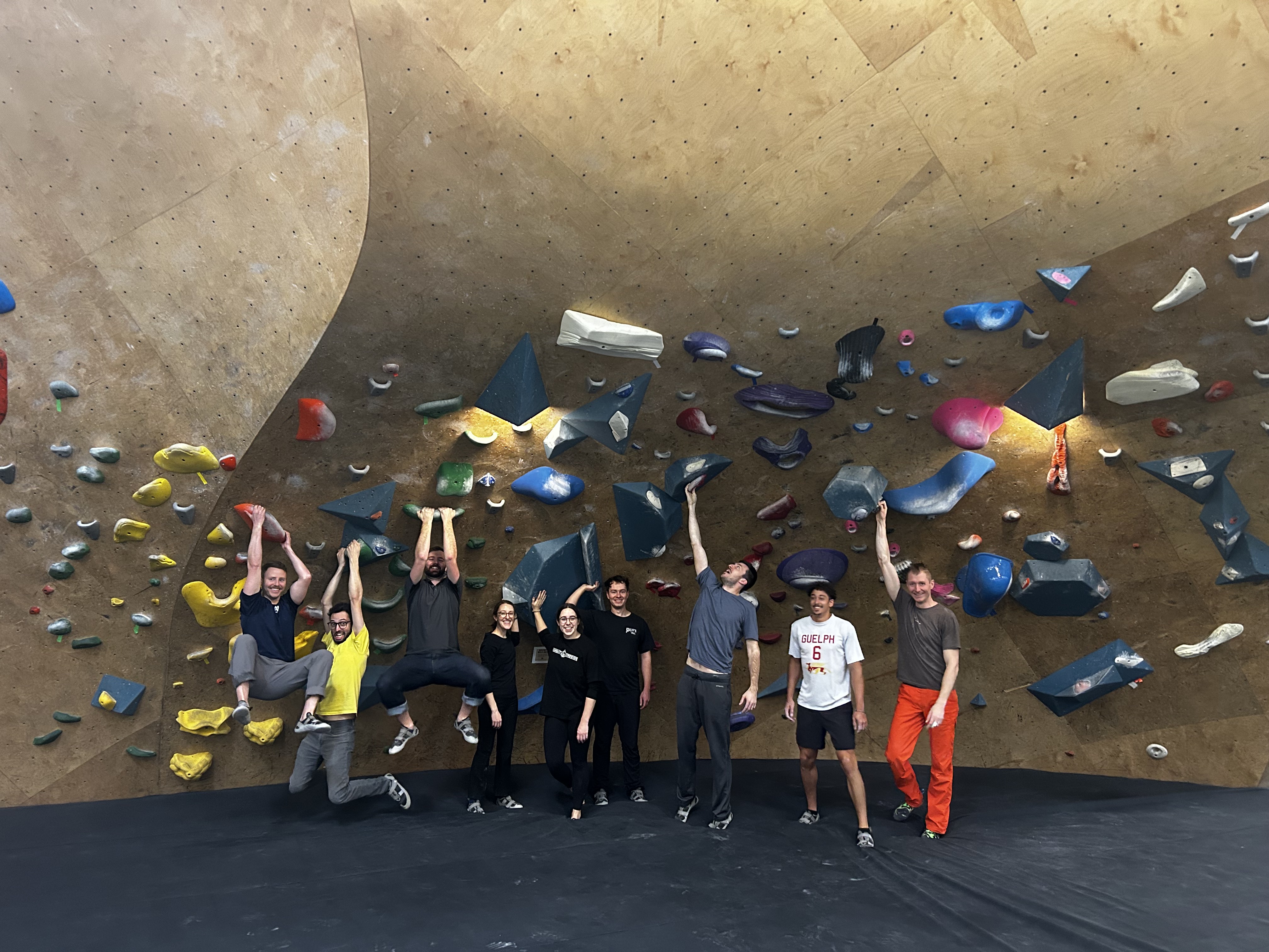 An image of Upstream Tech team members posing in front of an indoor climbing wall