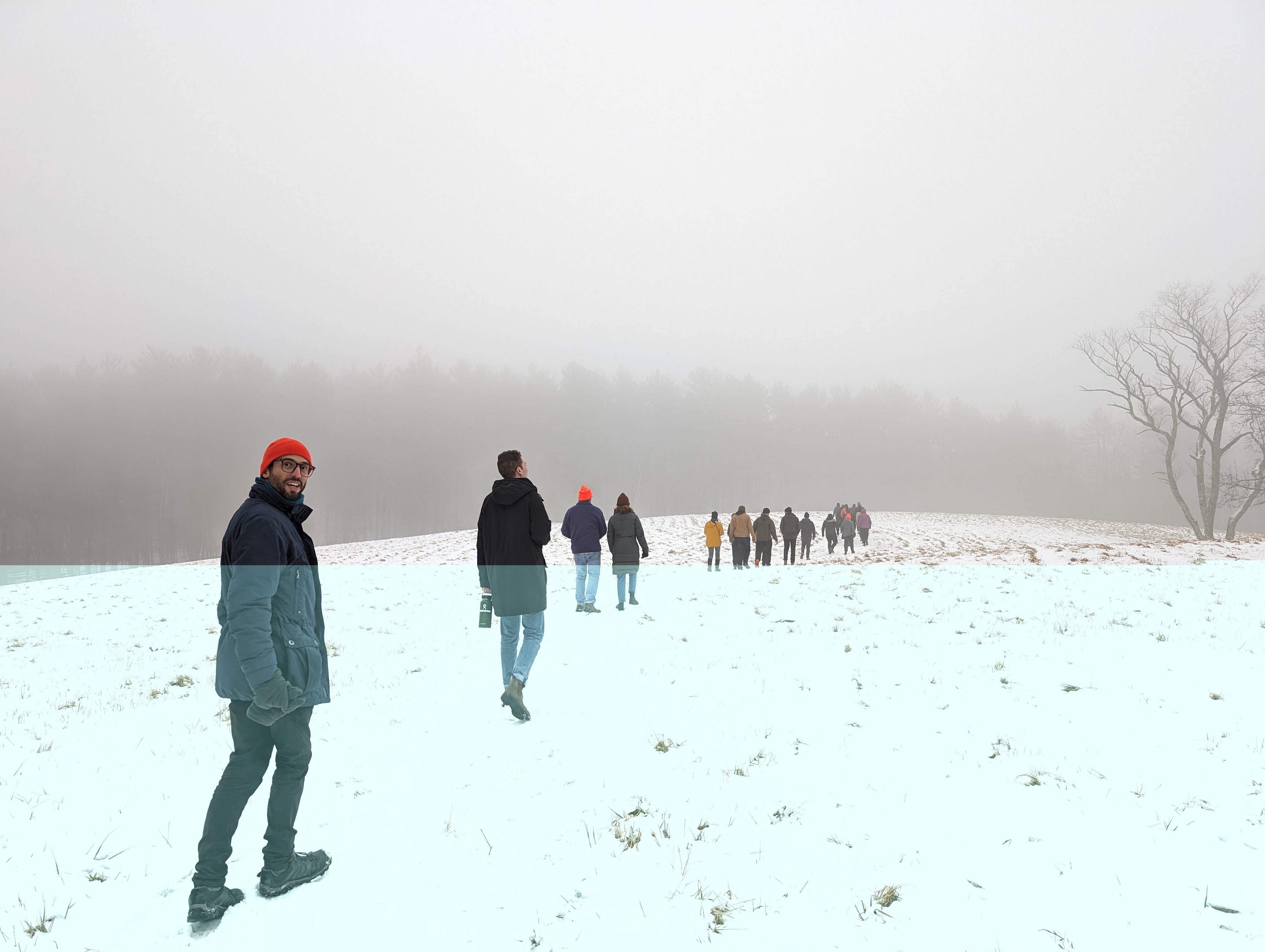 Team hiking in the snow, with the closest team member smiling into the camera.