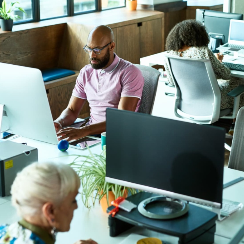 Photo of an office, with people at their desks working on computers