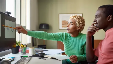 A man and a woman looking at a computer screen and pointing