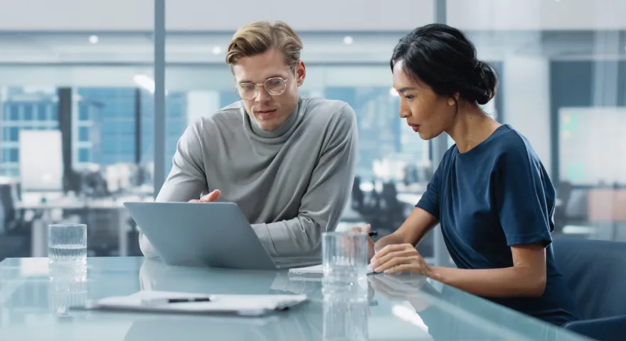 Colleagues discussing work while looking at a laptop