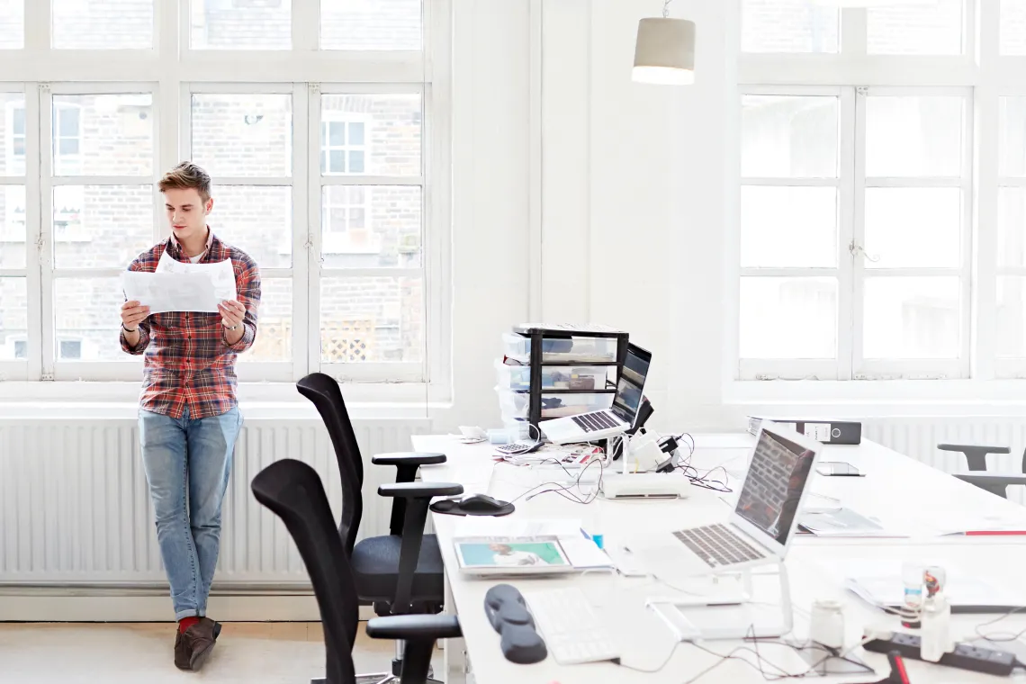 Casual businessman looking over documents while standing at a window