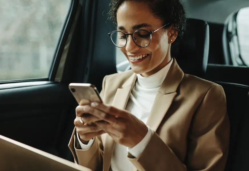 a person in a car smiling while looking at their phone