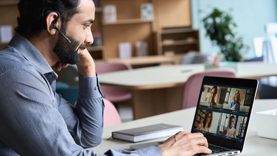 a man wearing headphones doing a remote call on a laptop