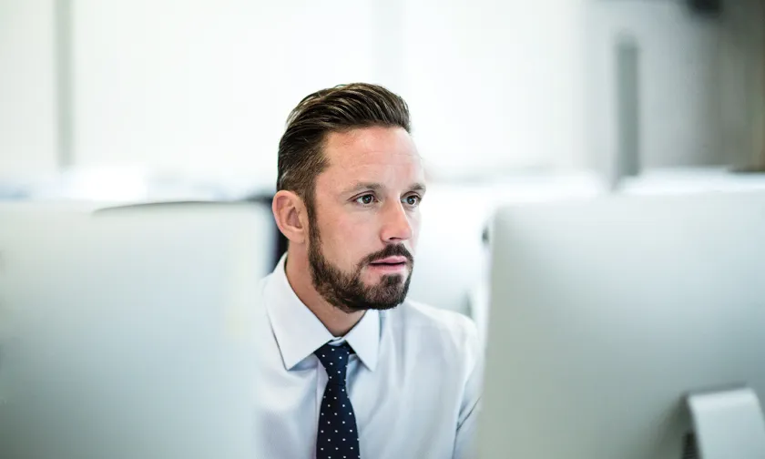 Man with a necktie looking at a computer monitor