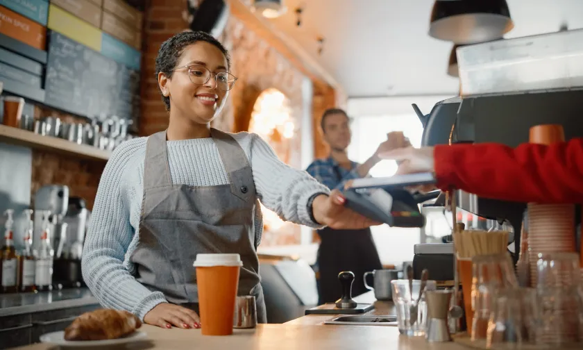 Woman taking a card payment in a coffee shop