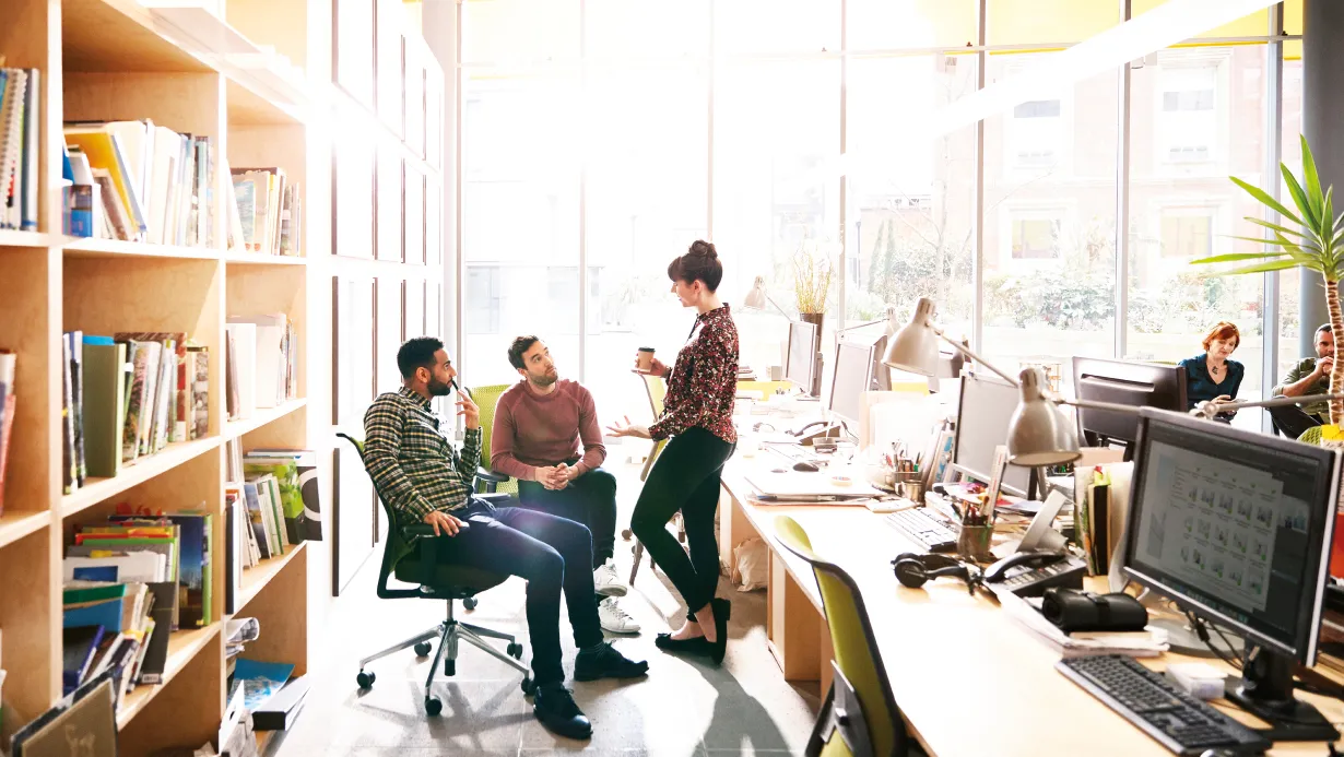 Team of casually dressed colleagues talking in an open office environment 