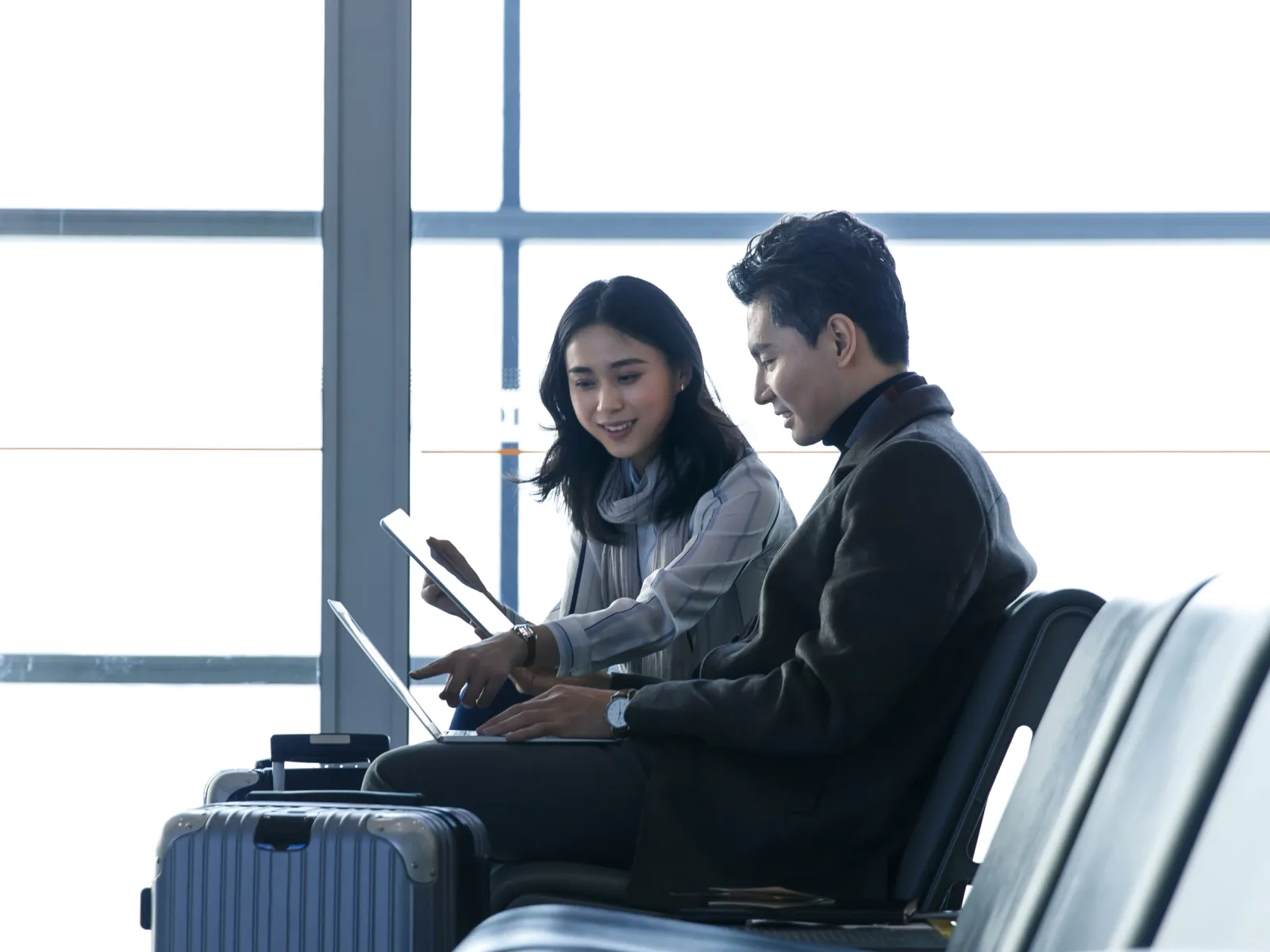 Business associates working on laptops while sitting in an airport terminal 