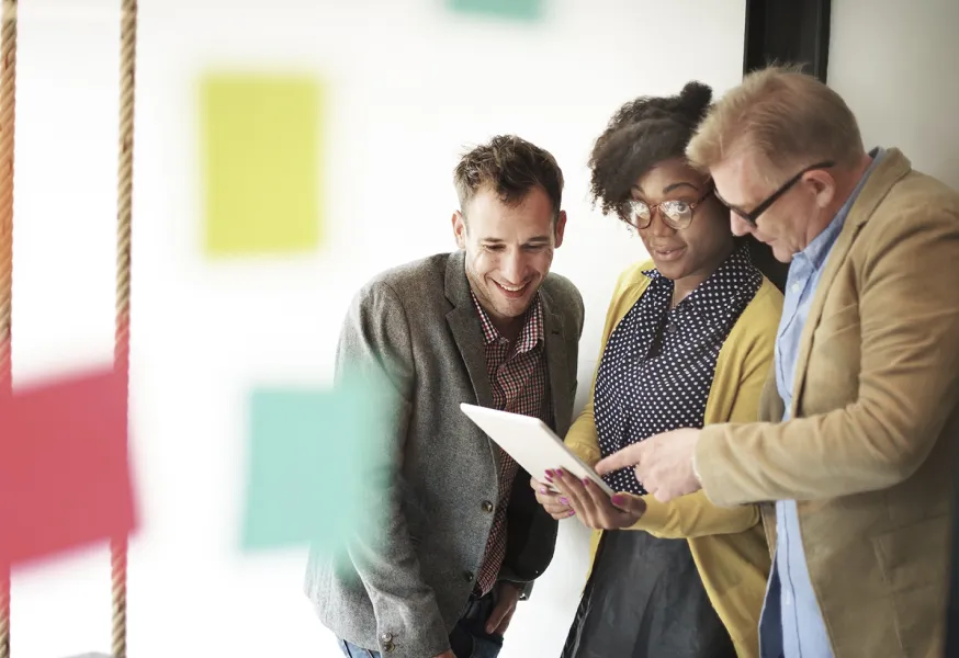 A group of people looking at a tablet and discussing 